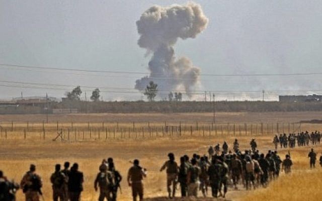 Smoke billows from an area near the Iraqi town of Nawaran, some 10km north east of Mosul, as Iraqi Kurdish Peshmerga fighters march down a dirt road on October 20, 2016, during the ongoing operation to retake the city from the Islamic State group. (AFP PHOTO / SAFIN HAMED) Smoke billows from an area near the Iraqi town of Nawaran, some 10km north east of Mosul, as Iraqi Kurdish Peshmerga fighters march down a dirt road on October 20, 2016, during the ongoing operation to retake the city from the Islamic State group. (AFP PHOTO / SAFIN HAMED)