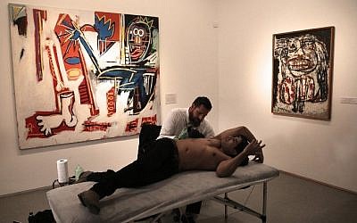 Luke Wessman tattoos Israeli war veteran Yogev Meushar, who was injured in 2006 in a Palestinian ambush in a West Bank city, during an event to use art to heal both mental and physical wounds, at the Israel Museum in Jerusalem, October 20, 2016. (AFP/Menahem Kahana)
