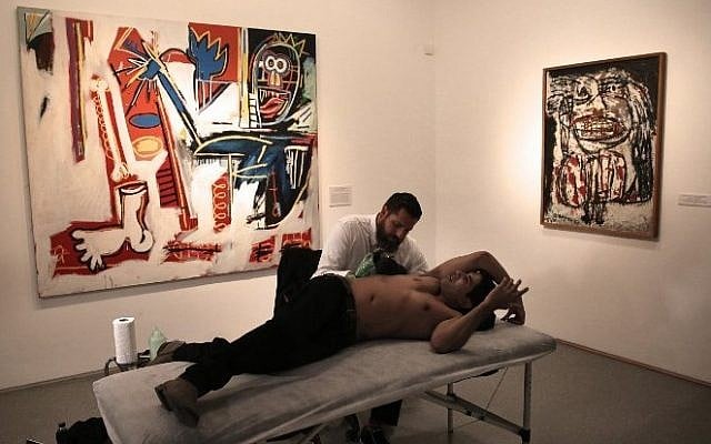 Luke Wessman tattoos Israeli war veteran Yogev Meushar, who was injured in 2006 in a Palestinian ambush in a West Bank city, during an event to use art to heal both mental and physical wounds, at the Israel Museum in Jerusalem, October 20, 2016. (AFP/Menahem Kahana)