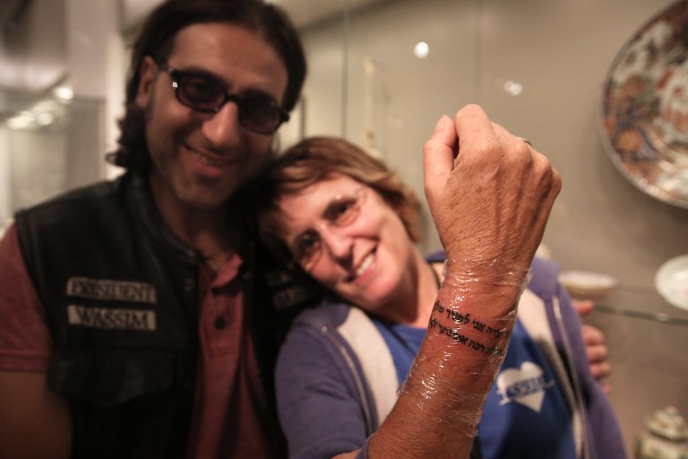 British-Israeli Kay Wilson displays the Hebrew prayer tattoo on her wrist, made by tattoo artist Wassim Razzouk, a Palestinian Christian from Jerusalem's Old City, as part of an initiative to use art to heal both mental and physical wounds at a modern art exhibition hall in the Israeli museum in Jerusalem on October 20, 2016. (AFP PHOTO / MENAHEM KAHANA) British-Israeli Kay Wilson displays the Hebrew prayer tattoo on her wrist, made by tattoo artist Wassim Razzouk, a Palestinian Christian from Jerusalem's Old City, as part of an initiative to use art to heal both mental and physical wounds at a modern art exhibition hall in the Israeli museum in Jerusalem on October 20, 2016. (AFP PHOTO / MENAHEM KAHANA)