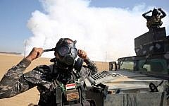 Iraqi forces wear gas masks for protection as smoke billows in the background after Islamic State (IS) group jihadists torched Mishraq sulphur factory, near the Qayyarah base, about 30 kilometres south of Mosul, during an operation to retake the main hub city from IS on October 22, 2016. (AFP/Ahmad Al-Rubaye)