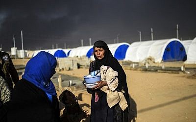 Smoke billows behind Iraqis as they arrive at refugee camp in the town of Qayyarah, south of Mosul, on October 22, 2016 (AFP/Bulent Kilic)
