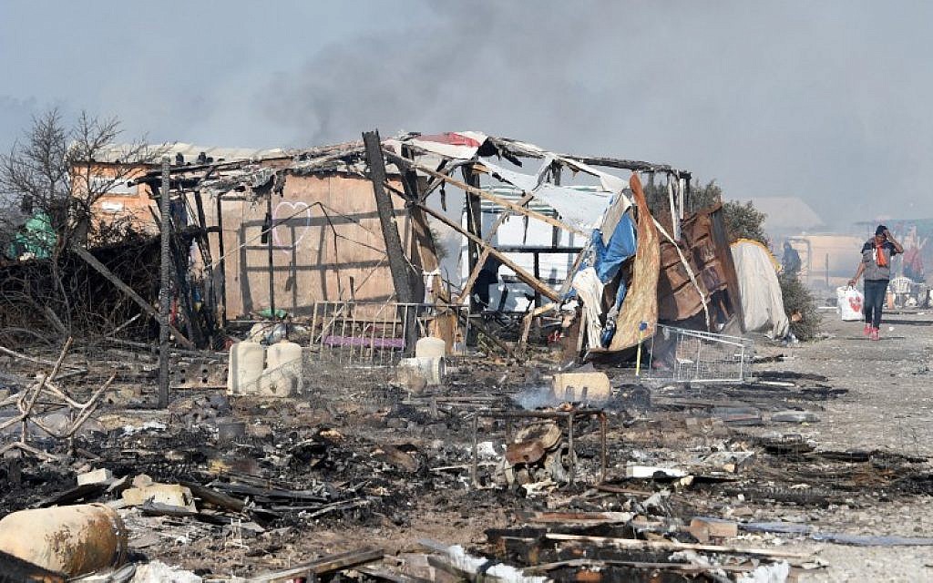 A migrant walks past a makeshift shelter destroyed by a fire at the 'Jungle' migrant camp in Calais, northern France, on October 26, 2016, during a massive operation to clear the squalid settlement where 6,000-8,000 people have been living in dire conditions. (AFP/DENIS CHARLET)