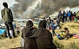 Migrants looks at the smoke rising from fires in the "Jungle" migrant camp in Calais, northern France, on October 26, 2016, during a massive operation to clear the squalid settlement where 6,000-8,000 people have been living in dire conditions. (Philippe Huguen/AFP)