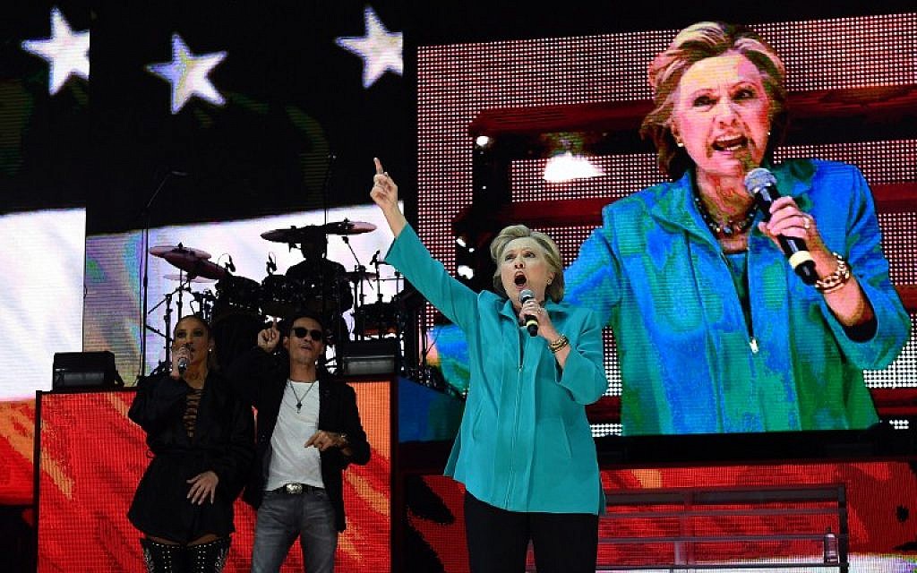 US Democratic presidential nominee Hillary Clinton speaks as singer Jennifer Lopez and Marc Anthony look on during 'Go Out to Vote' concert at the Bayfront Park Amphitheater in Miami, Florida, on October 29, 2016.  (AFP/Jewel SAMAD)