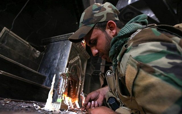 An Iraqi Christian forces member lights a candle at the Church of the Immaculate Conception on October 30, 2016 in the town of Qaraqosh (also known as Hamdaniya), 30 kms east of Mosul, after Iraqi forces recaptured it from Islamic State (IS) group jihadists. (AFP/ SAFIN HAMED) An Iraqi Christian forces member lights a candle at the Church of the Immaculate Conception on October 30, 2016 in the town of Qaraqosh (also known as Hamdaniya), 30 kms east of Mosul, after Iraqi forces recaptured it from Islamic State (IS) group jihadists. (AFP/ SAFIN HAMED)
