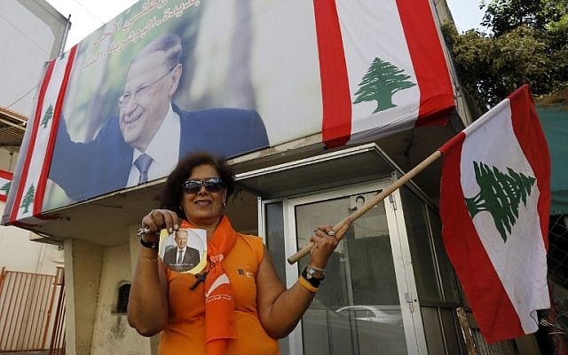 A supporter of Michel Aoun holds his portrait and the Lebanese flag on the outskirts of Beirut, ahead of the on October 31, 2016 parliament session that elected the ex-general as president and ended a political stalemate of more than two years. (AFP PHOTO/ANWAR AMRO)