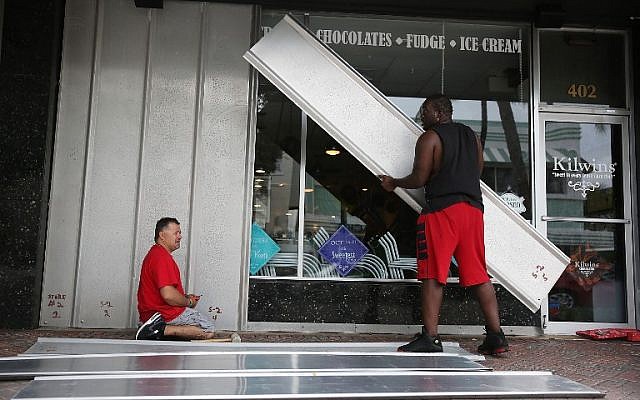 Local residents Jason Brock (L) and Kevin Hunter put up shutters in front of a business in Delray Beach as Hurricane Matthew approaches Florida on October 6, 2016. (Joe Raedle/Getty Images/AFP)
