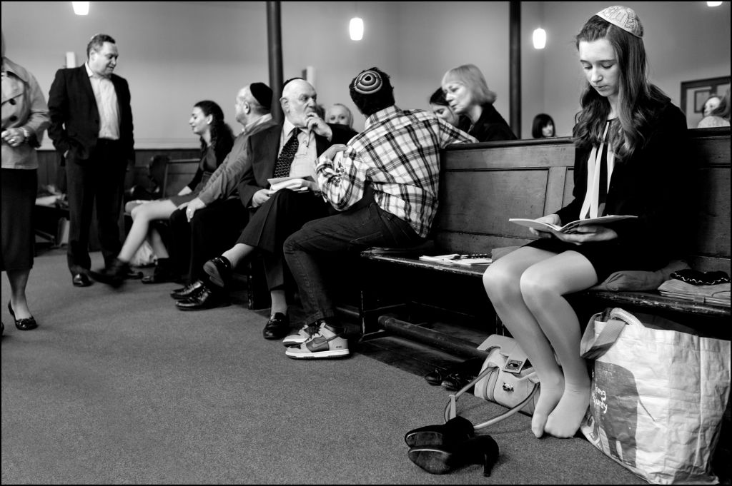 Scottish Jews at synagogue. Off to one side, a girl looks into her prayer book as other congregants talk to one another. (Judah Passow) Scottish Jews at synagogue. Off to one side, a girl looks into her prayer book as other congregants talk to one another. (Judah Passow)