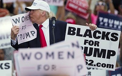 Republican presidential candidate Donald Trump kisses a "Women for Trump" sign during a campaign rally, Wednesday, Oct. 12, 2016, in Lakeland, Fla. (AP Photo/ Evan Vucci)
