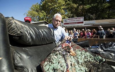 Republican vice presidential candidate, Indiana Gov. Mike Pence inspects a charred chair outside the Orange County Republican Party Headquarters in Hillsborough, N.C., Tuesday, Oct. 18, 2016. (AP/Ben McKeown)