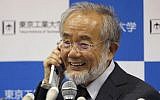 Nobel Prize winner Yoshinori Ohsumi smiles as he speaks with Japanese Prime Minister Shinzo Abe on a mobile phone during a press conference at the Tokyo Institute of Technology in Tokyo Monday, Oct. 3, 2016. (Shizuo Kambayashi/AP)