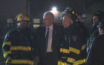 Republican vice presidential candidate Indiana Gov. Mike Pence talks with firefighters at New York's LaGuardia Airport after his campaign plane slide off the runway while landing on Thursday, Oct. 27, 2016. (TV Network Pool via AP)