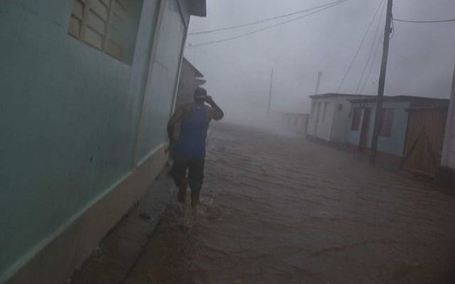 A resident runs in as flooded street as Hurricane Matthew roars over Baracoa, Cuba, Tuesday, October 4, 2016. (AP/Ramon Espinosa)