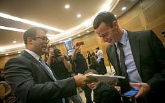 Likud MK Oren Hazan (L) hands Channel 2 News reporter Amit Segal a copy of the libel lawsuit Hazan filed against Segal, October 12, 2015. (Miriam Alster/Flash90)