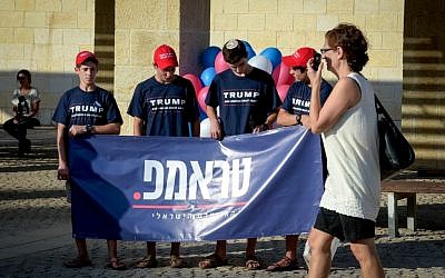 A woman walks by Trump supporters at the opening of the campaign supporting the Republican presidential candidate Donald Trump in Modiin on August 15, 2016. (Joe Davids/Flash90)
