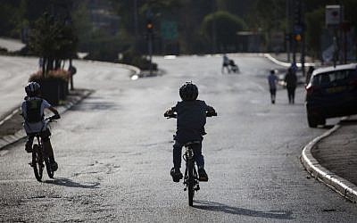 Children  ride bicycles on a road empty of cars in Jerusalem, on Yom Kippur, October 12, 2016 (Hadas Parush/Flash 90)