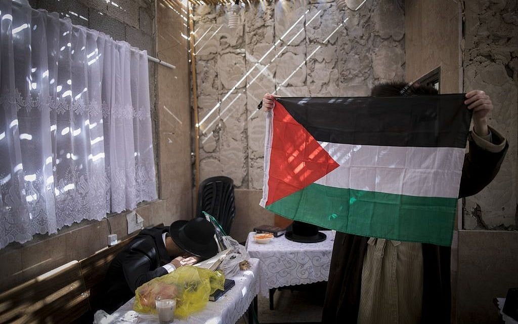 An ultra-Orthodox Jewish man holds up a Palestinian flag in a sukkah in the Jerusalem neighborhood of Mea Shearim on October 18, 2016. (Photo by Yonatan Sindel/Flash90)