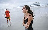 Emily Vulpi, 29, laughs as the winds pick up as she walks along the beach with Ryan Bell, 28, ahead of expected landfall of Hurricane Matthew in Daytona Beach, Florida, on Thursday, Oct. 6, 2016. (Will Vragovic/Tampa Bay Times via AP)
