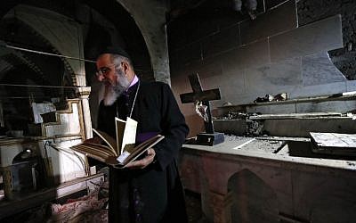 David Dosha, the priest of the Church of Mart Shmony, located in the Christian Iraqi town of Bartalla, about 15 kilometers (10 miles) east of Mosul, inspects the damage on October 24, 2016, at the church's compound after Iraqi forces retook control of the town from jihadists of the Islamic State group. (AFP/Safin Hamed)