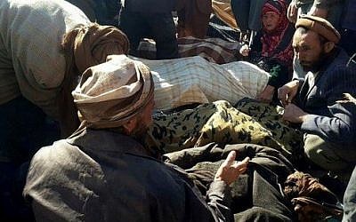 Afghan men and a woman gather around the bodies of civilians, including children, who were allegedly killed by Islamic State (IS) militants in Afghanistan‘s Ghor province on October 26, 2016. / AFP PHOTO / STRINGER