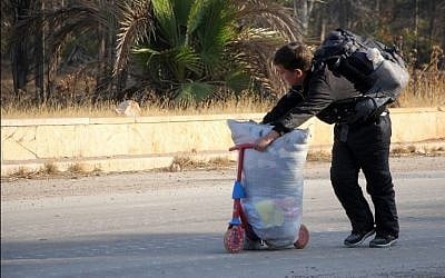 A Syrian youngster pushes his belongings on a scooter on October 30, 2016, as people leave Aleppo's southwestern frontline neighborhood of Dahiyet al-Assad, on the third day of a rebel offensive to break a three-month regime siege on the opposition-held east of Syria's second city. AFP PHOTO / Omar Haj Kadour