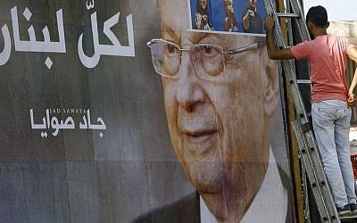 A worker hangs a billboard showing Christian leader Michel Aoun with Arabic that reads "For all Lebanon," in the southern port city of Sidon, Lebanon, Sunday, October 30, 2016. for President Bashar Assad in neighboring Syria. (AP Photo/Mohammed Zaatari)