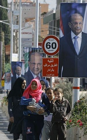 People walk past posters of Christian leader Michel Aoun in the southern port city of Sidon, Lebanon, Sunday, October 30, 2016. (AP Photo/Mohammed Zaatari)