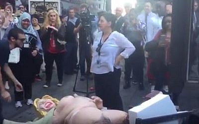 A woman stands over a statue of depicting a naked Democrat presidential nominee Hillary Clinton in New York, October 18, 2016. (Lenny Brook/YouTube)