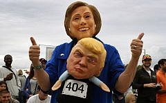 A woman wearing a Hillary Clinton mask carries a Republican presidential nominee Donald Trump doll during a Halloween parade in Long Beach, California on October 30, 2016. AFP / Mark RALSTON)