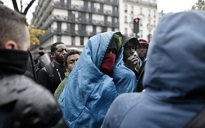 A man wrapped in a blanket stand as migrants wait to climb on a bus during an evacuation of a makeshift camp in Paris on November 4, 2016. (AFP Photo/Philippe Lopez)