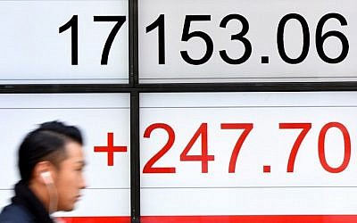 A businessman walks past an electric quotation board flashing the Nikkei key index of the Tokyo Stock Exchange (TSE) in front of a securities company in Tokyo on November 7, 2016.  (AFP / TORU YAMANAKA)