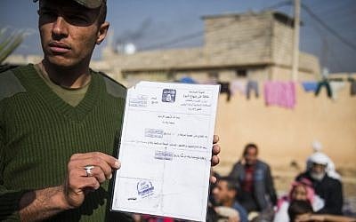 An Iraqi soldier from the Iraqi Army 9th armored division holds a death certificate issued by the Islamic State group next to a base adjacent to the Al-Intissar neighborhood of Mosul, on November 7, 2016. (AFP/Odd ANDERSEN)