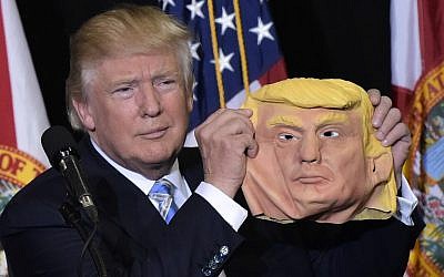 Republican presidential nominee Donald Trump holds a mask of himself which he picked up from supporter during a rally in the Robarts Arena of the Sarasota Fairgrounds in Florida on November 7, 2016.(AFP PHOTO/MANDEL NGAN)