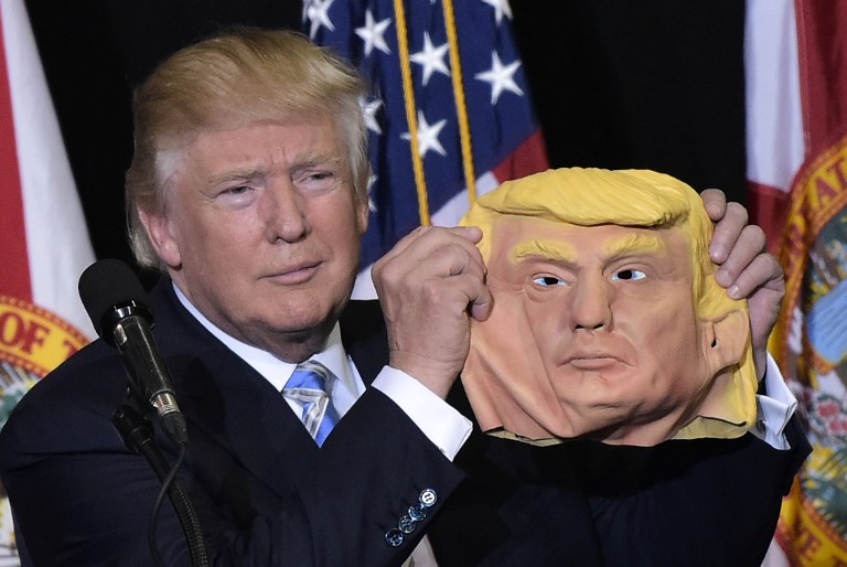 Republican presidential nominee Donald Trump holds a mask of himself which he picked up from supporter during a rally in the Robarts Arena of the Sarasota Fairgrounds in Florida on November 7, 2016.(AFP PHOTO/MANDEL NGAN) Republican presidential nominee Donald Trump holds a mask of himself which he picked up from supporter during a rally in the Robarts Arena of the Sarasota Fairgrounds in Florida on November 7, 2016.(AFP PHOTO/MANDEL NGAN)