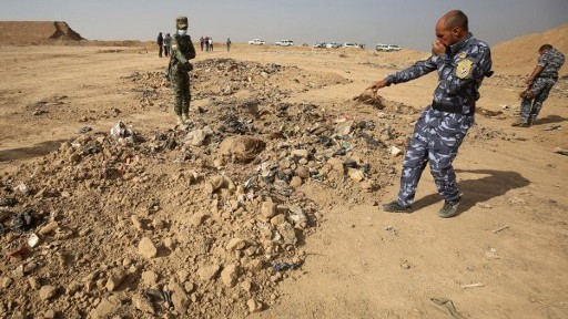 A member of the Iraqi forces checks a mass grave they discovered in the Hamam al-Alil area on November 7, 2016 after they recaptured the area from Islamic State (IS) group jihadists during the ongoing operation to retake Mosul, the last IS-held Iraqi city. (AHMAD AL-RUBAYE / AFP) A member of the Iraqi forces checks a mass grave they discovered in the Hamam al-Alil area on November 7, 2016 after they recaptured the area from Islamic State (IS) group jihadists during the ongoing operation to retake Mosul, the last IS-held Iraqi city. (AHMAD AL-RUBAYE / AFP)