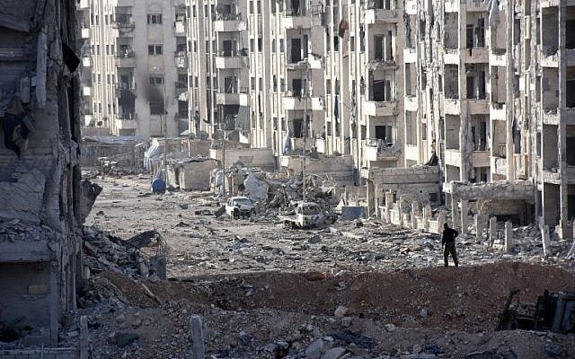 A member of the Syrian pro-government forces stands amid heavily damaged buildings in Aleppo's 1070 district on November 8, 2016, after troops seized it from rebel fighters. AFP PHOTO / GEORGES OURFALIAN) 