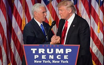 Republican president-elect Donald Trump (R) shakes hands with his running mate Mike Pence at the New York Hilton Midtown in New York on November 9, 2016. (AFP PHOTO/JIM WATSON)