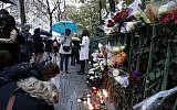 People gather around flowers and candles laid next to the Bataclan concert hall in Paris on November 12, 2016, a few hours before the reopening concert by British musician Sting to mark the first anniversary of the November 13 Paris attacks.(AFP PHOTO / FRANCOIS GUILLOT)