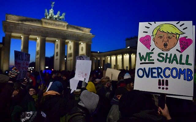 A demonstrator protesting against US president-elect Donald Trump displays a placard featuring a likeness of Trump during a demonstration at Berlin's Brandenburg Gate on November 12, 2016. (AFP / John MACDOUGALL)