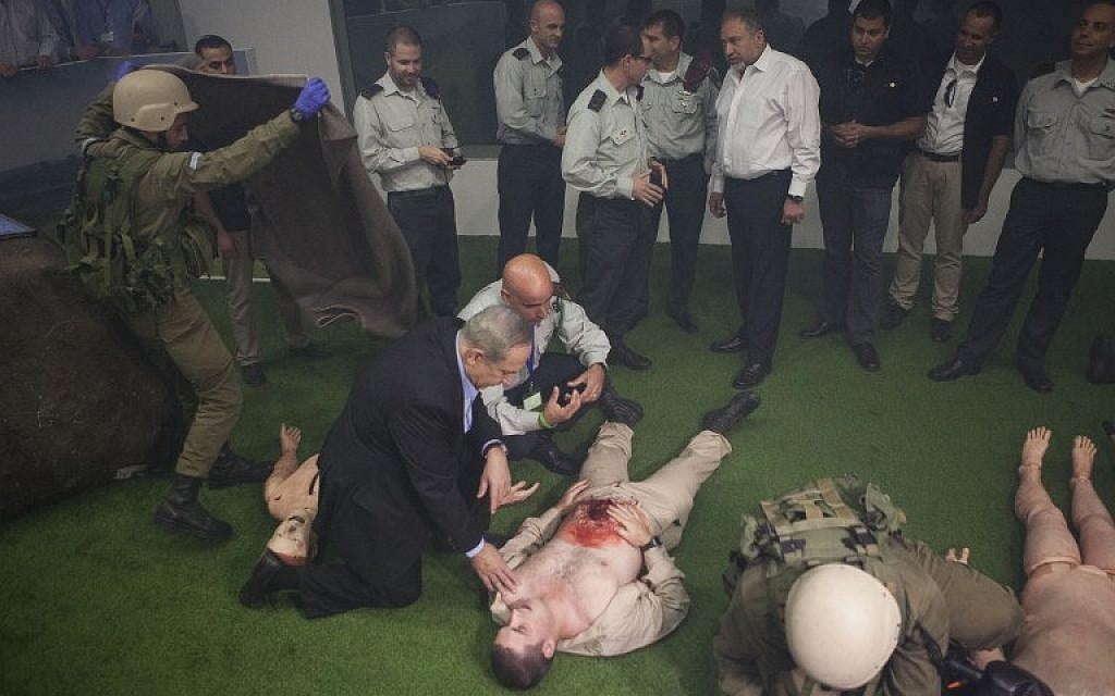 Prime Minister Benjamin Netanyahu (L) and Israeli defense Minister Avigdor Lieberman (4-R), are seen next to soldiers doing a rescue simulation during a visit at the new training military base next to the southern city of Beer Sheva on November 15, 2016. (AFP PHOTO / POOL AND AFP PHOTO / Dan Balilty)