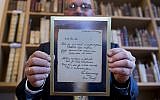 A man shows a handwritten poem by Anne Frank, written shortly before she went into hiding from the Nazis, at the auction Bubb Kuyper in Haarlem on November 22, 2016. (AFP PHOTO / ANP / Koen Suyk / Netherlands)
