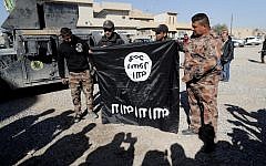 Iraqi army soldiers hold a flag from the Islamic State jihadist group up-side-down on November 23, 2016, near an Iraqi army base in the outskirts of Mosul. (AFP/Thomas Coex)