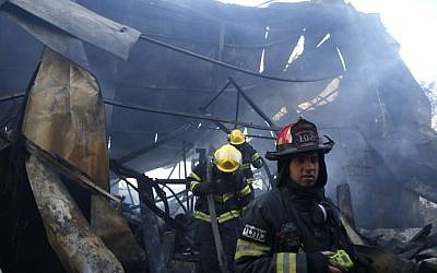 An Israeli firefighter inspects the damages in Beit Meir in the hills to the west of Jerusalem, on November 25, 2016. (AFP/AHMAD GHARABLI)