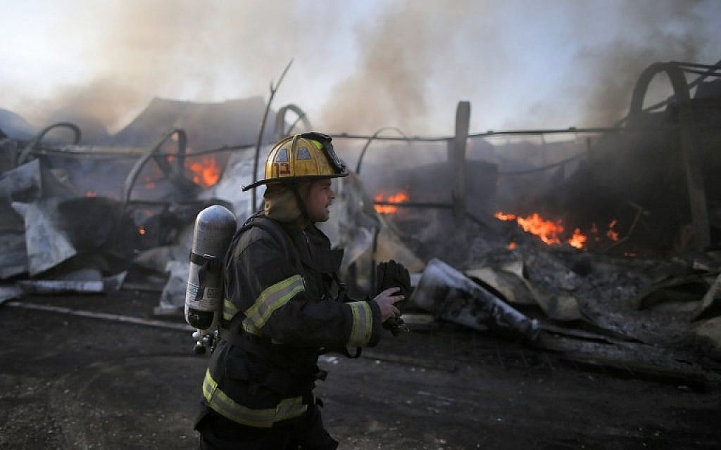 An Israeli firefighter inspects the damages in Beit Meir in the hills to the west of Jerusalem, on November 25, 2016. (AFP/AHMAD GHARABLI)
