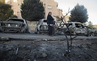 A woman stands amid the damage and burned vehicles in the northern Israeli city of Haifa following a wildfire, on November 25, 2016. (AFP/Jack Guez)