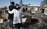 Israeli settlers grieve over their burnt houses in the Halamish settlement on November 27, 2016. AFP / MENAHEM KAHANA)
