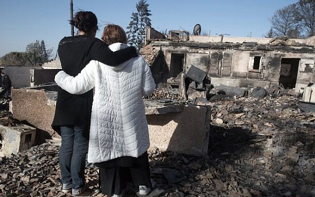 Israeli settlers grieve over their burnt houses in the Halamish settlement on November 27, 2016. AFP / MENAHEM KAHANA)