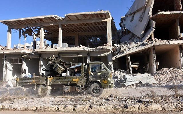 A vehicle of Syrian pro-government forces drives past damaged buildings in the Masaken Hanano district in eastern Aleppo, November 27, 2016. (AFP/GEORGE OURFALIAN)