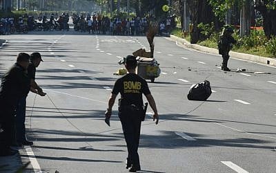 A member of police bomb disposal unit (R) holding a water bomb disruptor, walks towards the site where a suspicious package was found, for detonation along Roxas boulevard near the US embassy in Manila on November 28, 2016. (AFP PHOTO / TED ALJIBE)